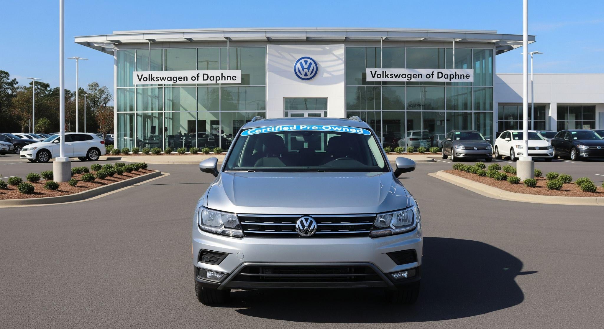 Certified pre-owned Volkswagen SUV displayed at Volkswagen of Daphne, with signage visible and dealership lot in the background under sunny skies.